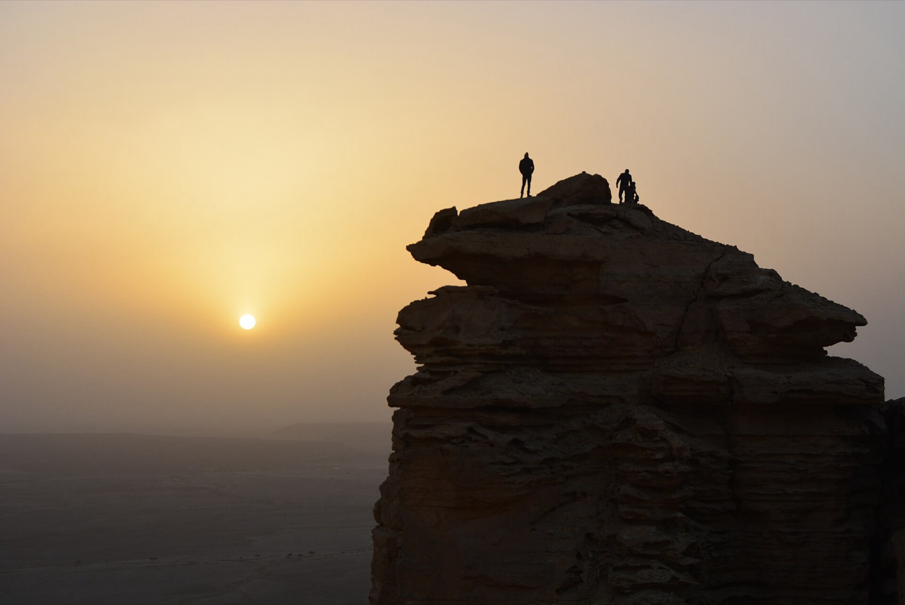 Two people on a cliff at the Edge of the World near Riyadh at sunrise