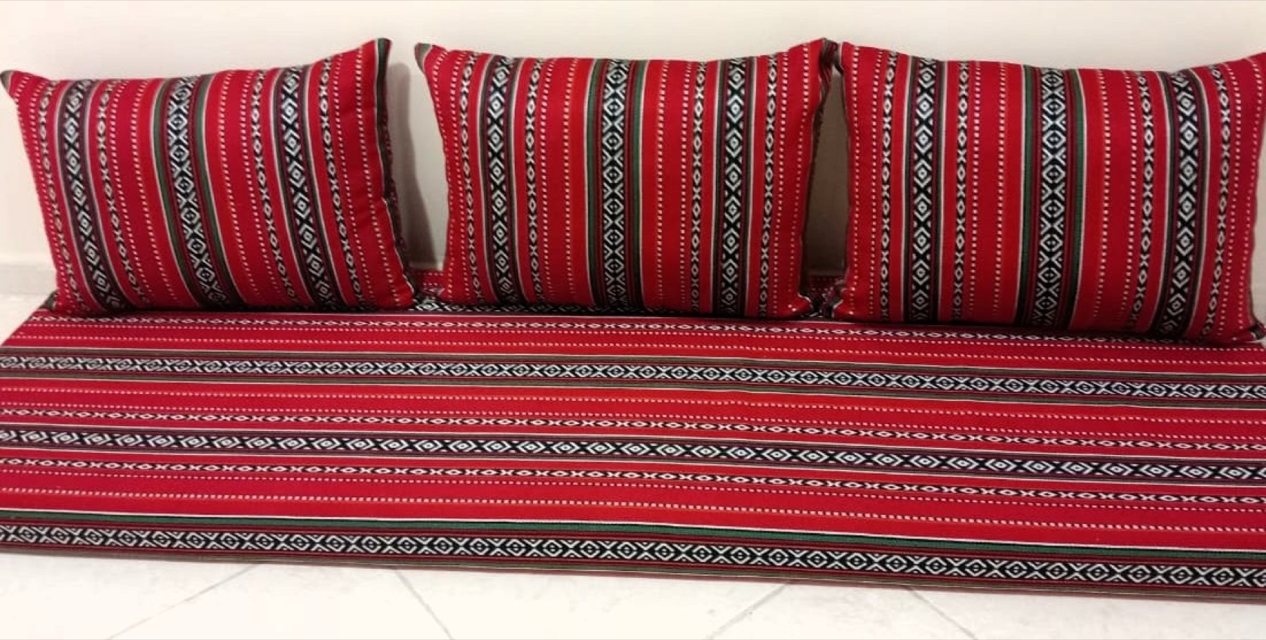 A majlis with red Sadu‑woven cushions